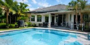 Heat pump pool heater hidden in a fenced side yard between a stucco wall and wooden fence