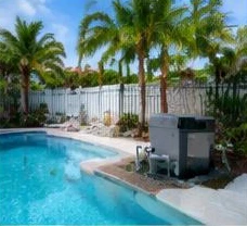 Heat pump pool heater hidden in a fenced side yard between a stucco wall and wooden fence