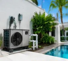 Heat pump pool heater hidden in a fenced side yard between a stucco wall and wooden fence
