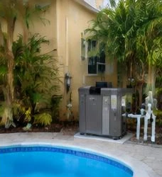Heat pump pool heater hidden in a fenced side yard between a stucco wall and wooden fence