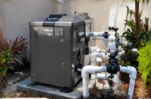 Heat pump pool heater hidden in a fenced side yard between a stucco wall and wooden fence