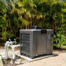 Heat pump pool heater hidden in a fenced side yard between a stucco wall and wooden fence