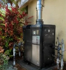 Heat pump pool heater hidden in a fenced side yard between a stucco wall and wooden fence