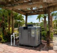 Heat pump pool heater hidden in a fenced side yard between a stucco wall and wooden fence