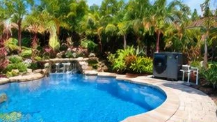 Heat pump pool heater hidden in a fenced side yard between a stucco wall and wooden fence