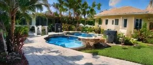 Heat pump pool heater hidden in a fenced side yard between a stucco wall and wooden fence