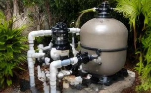 Heat pump pool heater hidden in a fenced side yard between a stucco wall and wooden fence