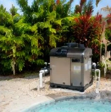 Heat pump pool heater hidden in a fenced side yard between a stucco wall and wooden fence