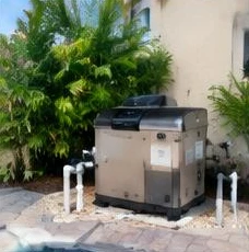 Heat pump pool heater hidden in a fenced side yard between a stucco wall and wooden fence