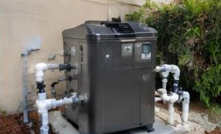 Heat pump pool heater hidden in a fenced side yard between a stucco wall and wooden fence