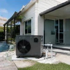 Heat pump pool heater hidden in a fenced side yard between a stucco wall and wooden fence