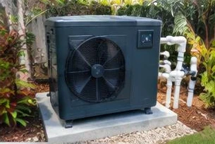 Heat pump pool heater hidden in a fenced side yard between a stucco wall and wooden fence