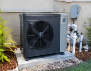 Heat pump pool heater hidden in a fenced side yard between a stucco wall and wooden fence